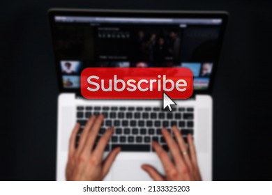 Subscribe now. Online video subscription red button. Internet service on laptop digital tablet blured technology background. Streaming video. Communication network