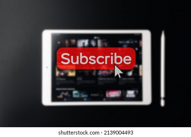Subscription plan. Red online video subscribe button. Internet service on laptop digital tablet blured technology background. Visual contents concept. Social networking service
