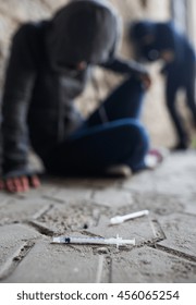 Substance Abuse, Addiction, People And Drug Use Concept - Close Up Of Addicts And Used Syringes On Ground