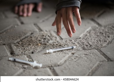 substance abuse, addiction, people and drug use concept - close up of addict woman hands and used syringes on ground - Shutterstock ID 458044624