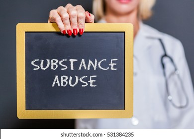 Substance Abuse Chalkboard Sign Held By Female Doctor In Dark Room.