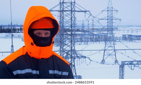 Substation worker in bright jacket transmitting readings via radio. Harsh winter conditions need for precise communication to maintain stable substation operations Work in cold weather