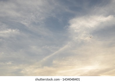 Subtle Background Of Sunset Sky And Clouds In Rainy Season With Golden Yellow Grey White  And Blue Shades, Tiny Airplane On Right Middle.