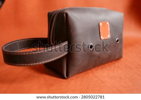 The bag’s subtle distressed texture and precise stitching convey premium craftsmanship; its compact form and secure zip closure make it ideal for travel and daily use