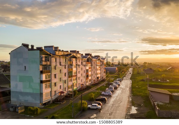 Suburb landscape,\
apartment building. Parked cars along bad road on spring day on\
blue sky copy space\
background.