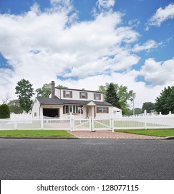 Suburban High Ranch White Picket Fence Brick Driveway Residential Neighborhood Street Blue Sky Clouds