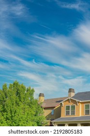 Suburban Home And Bushy Green Tree With A Wide Open Sky And Wispy Clouds With Plenty Of Copy Space