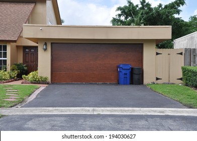 Suburban Home Recycle Trash Can In Front Of Wood Two Car Garage Residential Neighborhood USA