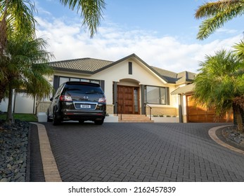 Suburban house with black Mazda MPV parked in front. Auckland, New Zealand - May 20, 2022