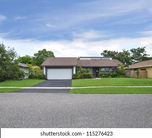 Suburban Ranch Style Home Blacktop Driveway One Car Garage Landscaped Front Yard Lawn