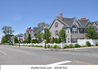 Suburban Three Story Tall Condominium Neighborhood Street American Flag Waving In Air Sunny Blue Sky Day