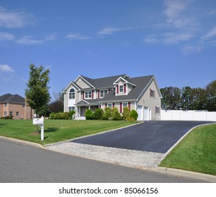 Suburban Two Story Double Garage Home With Fancy Blacktop Cobble Stone Driveway Mailbox On Curb Sunny Blue Sky Day