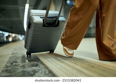 In the subway, a businesswoman with takeaway coffee in hand pulls a suitcase. - Powered by Shutterstock