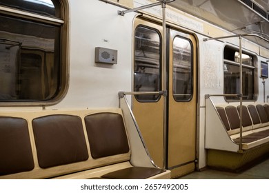 Subway interior features empty brown seats and glass doors, illustrating the calm atmosphere in a public transport system during non-peak times.