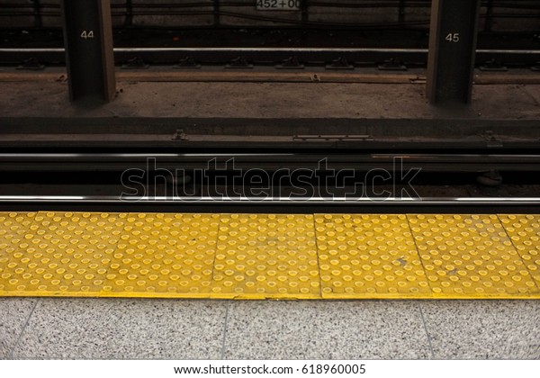subway platform with safety yellow flooring at\
edge of station platform