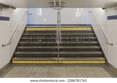 Subway stairs with hand rails, low ceilings and tiled walls in downtown Manhattan