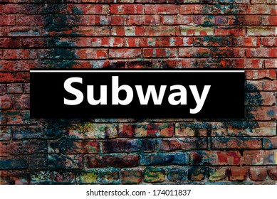 Subway or Underground sign board on a graffiti laden brick wall