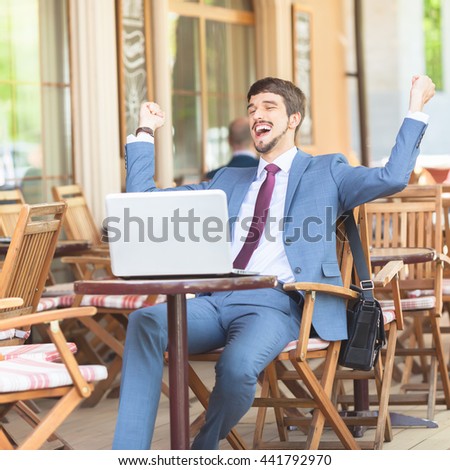Succesful man hands up outdor at French cafe, restauran, Paris. Using laptop. Concept of succes deal. Onlin banking.