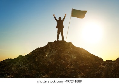 Success And Achievement Concept , Silhouette Of Businessman With Flag On Mountain Top .