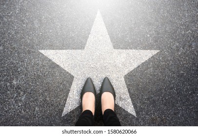 Success in business design concept. Businesswoman standing on street road background. Top view. Selfie of feet in black high heels shoes and white star symbol on pathway floor. New talent or champion.