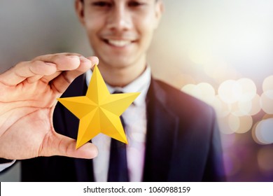 Success in Business or Personal Talent Concept. Happy Businessman in black suit Smiling and Showing a Golden Star in Hand