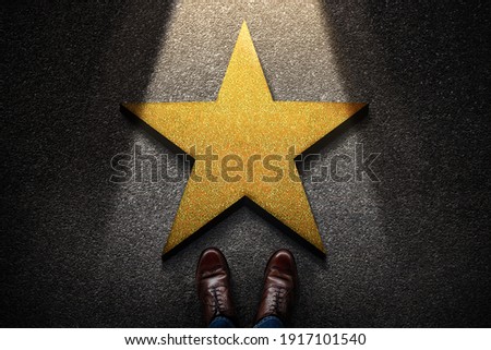Success in Business or Personal Talent Concept. Top View of Business Person in Working Shoes Standing in front of a Golden Star. Light Shining on the Dark Cement Floor