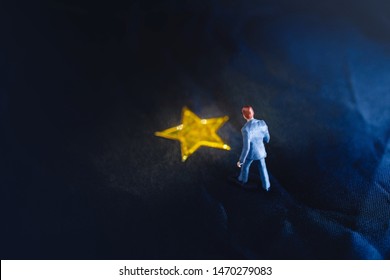 Success In Business Or Talent Concept. Top View Of A Miniature Businessman Standing On A Yellow Golden Star