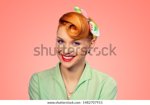 Success. Closeup portrait beautiful radiant\
businesswoman looking at you camera isolated peach color pink\
background.  Pinup girl retro vintage clothing 50\'s  hairstyle\
smiling Positive human\
emotions