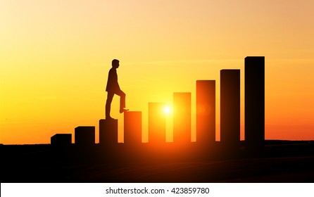 Success concept with businessman silhouette climbing chart bars at sunset