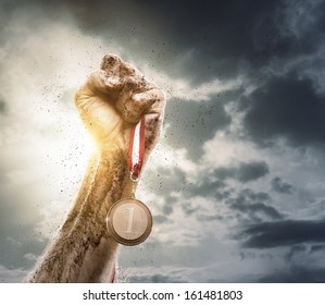 Success concept, male hand rise up a gold medal against the dramatic sky with copy space - Powered by Shutterstock