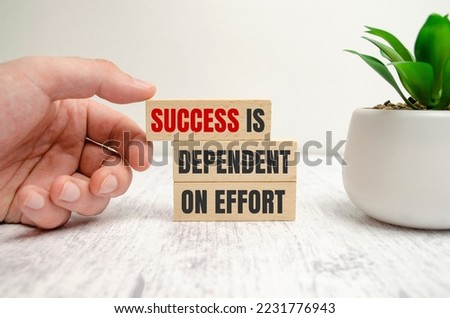 Success is Dependent on Effort sign on wooden blocks with man hand