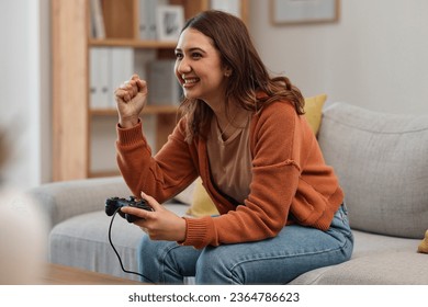 Success, happy and a woman gaming on the sofa with a win, celebration and excited about competition. Smile, house and a girl with a console for a game, entertainment and achievement with technology - Shutterstock ID 2364786623