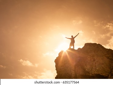 Success, life goals, fitness and achievement concept. Man standing on edge of mountain feeling victorious with arms up in the air.