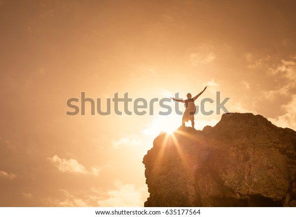 Success, life goals, fitness and achievement\
concept. Man standing on edge of mountain feeling victorious with\
arms up in the air.
