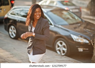 Success Stylish African American Woman In Jacket Against Black Car.