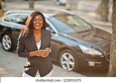 Success Stylish African American Woman In Jacket Against Black Car.