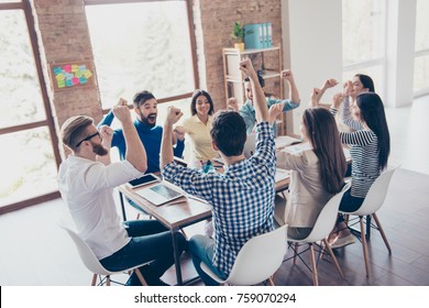 Success And Team Work Concept. Team Of Business Partners With Raised Up Hands In Light Modern Workstation, Celebrating The Breakthrough In Their Company