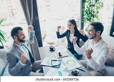 Success And Team Work Concept. Group Of Business Partners With Raised Up Hands In Light Modern Terrace Of A Fancy Restaurant, Celebrating The Breakthrough In Their Company