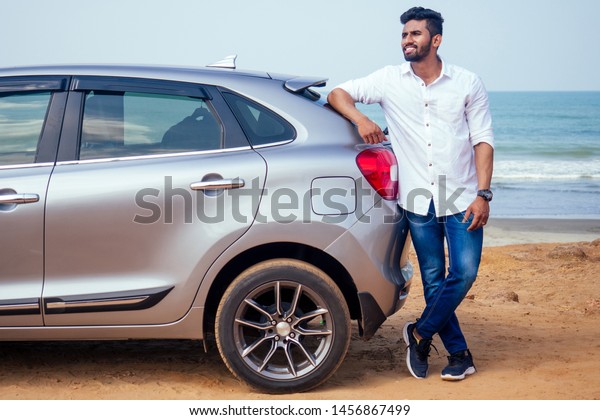 success traveler driver
indian model male in a white shirt freelancer smiling and posing
seacost .Handsome bearded man is standing near car freelancing on
the beach