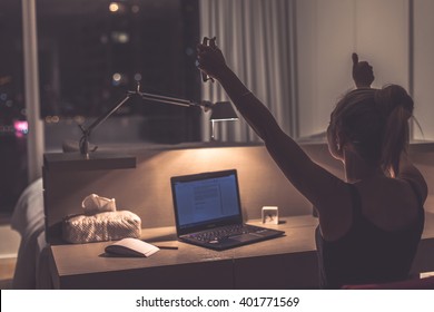 Success, victory or meeting deadline concept. Young,excited caucasian woman or teenager is holding her hands up in the air. Female teenager working late at night in her room. Success concept. - Shutterstock ID 401771569