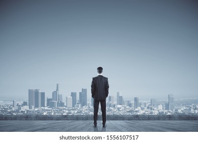 Success, vision and future concept. Back view of businessman looking into distance on rooftop with daylight city view. Copy space. - Powered by Shutterstock