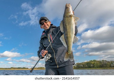 Success zander fishing. Happy fisherman with big walleye fish trophy at lake