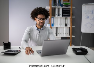 Successful Accountant Calculating Tax At Office Desk Using Laptop