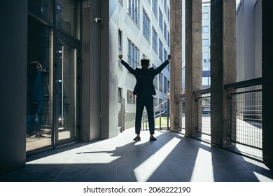 Successful african american businessman with arms up celebrating victory. Concept: success, career growth, victory, freedom. silhouette business man on the background a modern office building. outside - Powered by Shutterstock