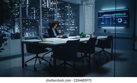 Successful African American Businesswoman Walking into Meeting Room in Big City Office Late in the Evening. Female Executive Director Opens Laptop, Analyzes Financial Reports. Project Manager at Work.