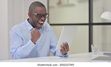 Successful African Man Celebrating on Tablet at Work 