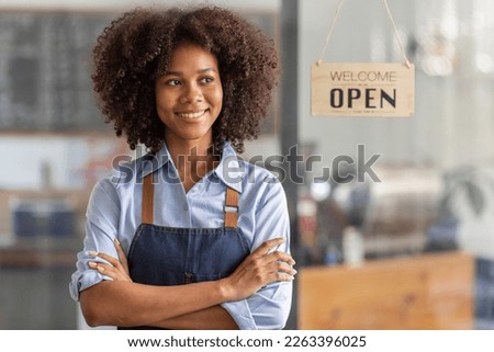 Successful african woman in apron standing coffee shop door. Happy small business owner holding tablet and working. Smiling portrait of SME entrepreneur seller business standing with copy space.