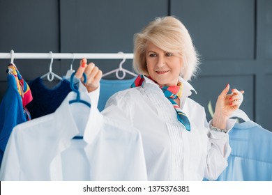 Successful Aged Woman. Clothes Boutique Business. Personal Fashion Stylist. Confident Senior Lady With Clothes On Hangers.