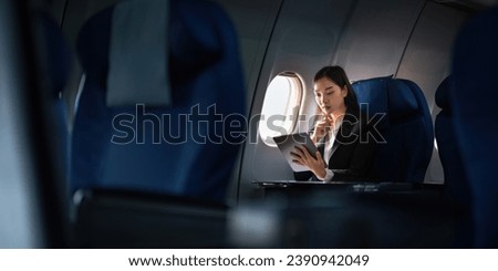 Successful Asian business woman, Business woman working in airplane cabin during flight on tablet