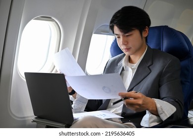 Successful Asian businessman concentrating working, preparing a meeting documents, reading a report during the flight for his business trip. Business and transportation concept - Powered by Shutterstock